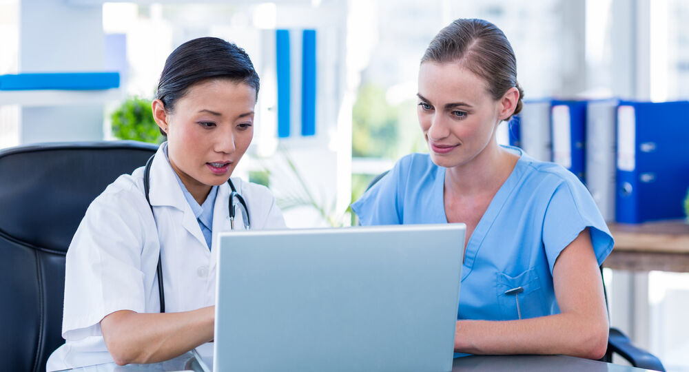 Doctor,And,Nurse,Looking,At,Laptop,In,Medical,Office